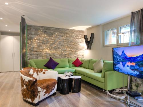Il comprend un salon doté d'un canapé vert et d'une télévision à écran plat. dans l'établissement Apartment Dione by Interhome, à Zermatt