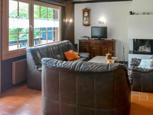 a living room with a leather couch and a tv at Apartment Chalet l'Aube by Interhome in Vers L'Eglise