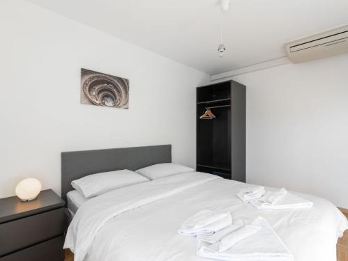 a bedroom with a white bed and a black cabinet at Apartment Vasco de Gama B11-R by Interhome in Bouveret