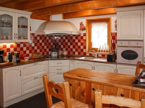 una cucina con armadi bianchi, tavolo e finestra di Chalet Dörfli by Interhome a Les Diablerets