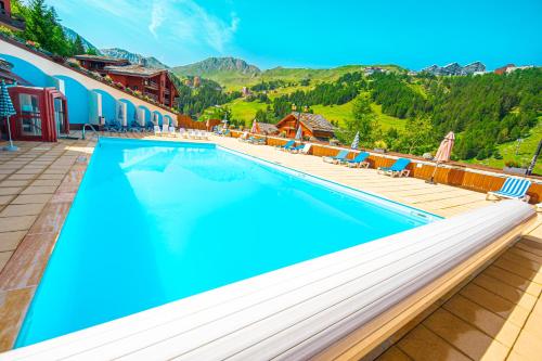 a swimming pool at a resort with mountains in the background at Le Panoramix in Plagne 1800