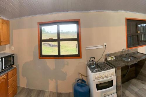 a kitchen with a stove and a sink and a window at Casa de Campo Cambará in Cambará