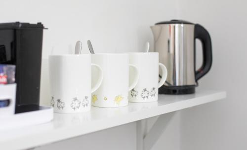 four white coffee cups sitting on a shelf at The Tiger Inn in Merthyr Tydfil