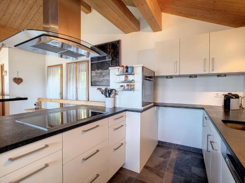 a kitchen with white cabinets and black counter tops at Chalet Le Dahu by Interhome in Veysonnaz