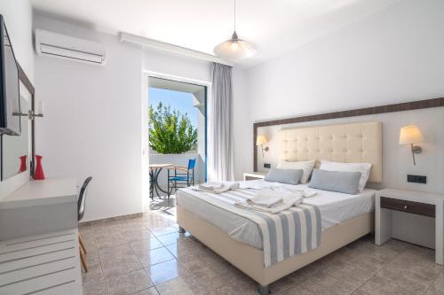 a white bedroom with a bed and a table at Mythos Apartments in Damnoni