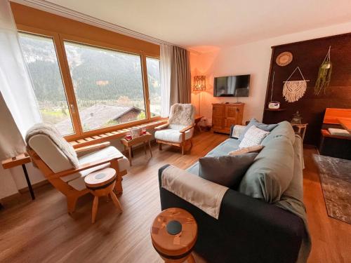 a living room with a couch and a large window at Apartment SnowKaya Grindelwald by Interhome in Grindelwald
