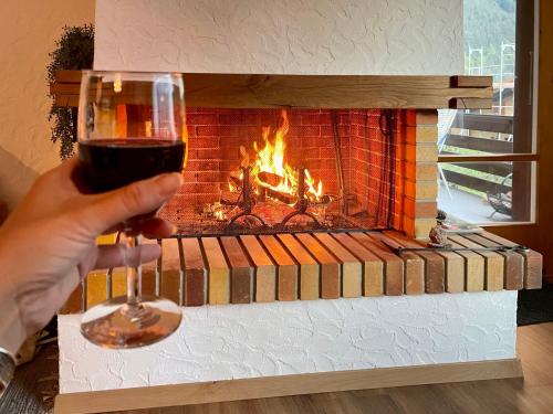 a person holding a glass of wine in front of a fireplace at Apartment SnowKaya Grindelwald by Interhome in Grindelwald
