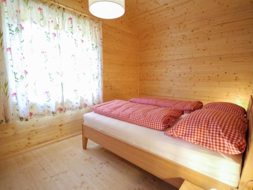 a bed in a wooden room with a window at Chalet Stressless by Interhome in Presseggen