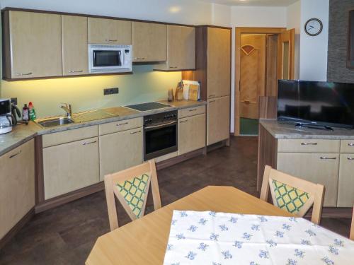 una cocina con armarios de madera, mesa y sillas en Apartment Alpenflora by Interhome en Kappl