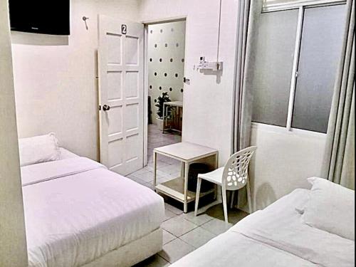 a small room with two beds and a table and a chair at Ozzy Lodge Semporna in Semporna