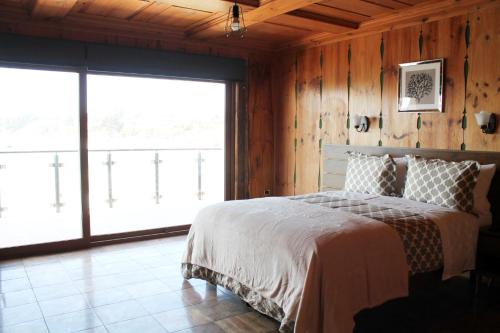 a bedroom with a bed and a large window at Costanera240 in El Quisco