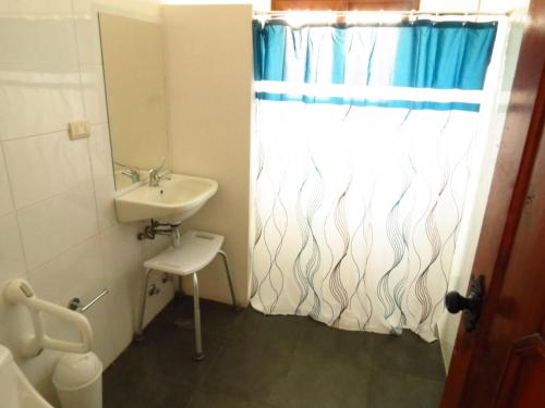 a bathroom with a sink and a shower curtain at Costanera240 in El Quisco