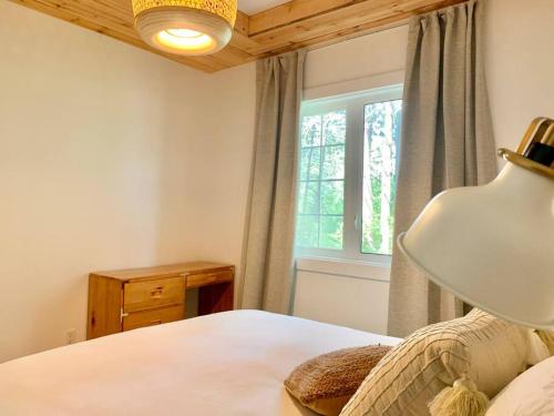 um quarto com uma cama com um candeeiro e uma janela em Le bohémien - Condos Saint-Côme em Saint Come