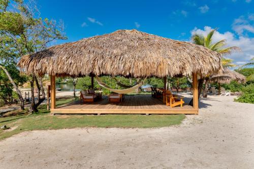 a hut with a hammock and a straw roof at Barefoot Cay Resort in Roatan