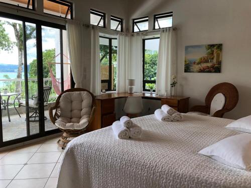 a bedroom with two beds and a desk and windows at Villa Corazón - private beach at Lake Arenal in Nuevo Arenal