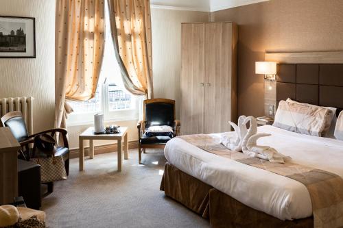 ein Hotelzimmer mit einem Bett und einem Stuhl in der Unterkunft Hotel Regina & Spa in Berck-sur-Mer