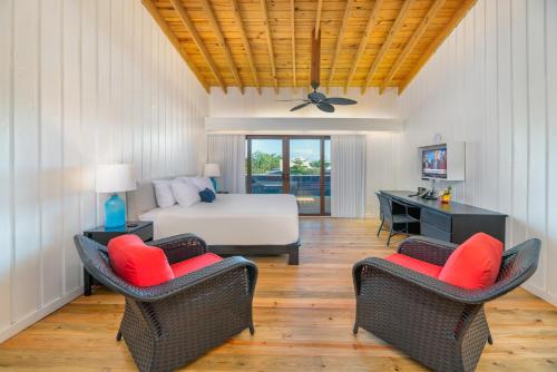 a bedroom with a bed and two chairs at Barefoot Cay Resort in Roatan
