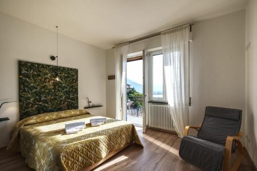 a bedroom with a bed and a chair and a window at Ca Belee by Halldis in Vercana