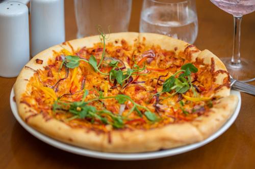 a pizza sitting on top of a plate on a table at Pods at Broadway in Laugharne