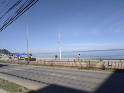 a person walking on the beach near the ocean at Departamento, Playa Bellavista, Tomé in Tomé