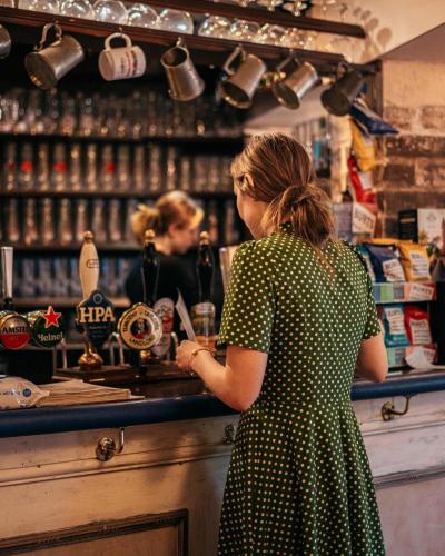 a woman in a polka dot dress standing at a bar at The Mug House Inn in Bewdley