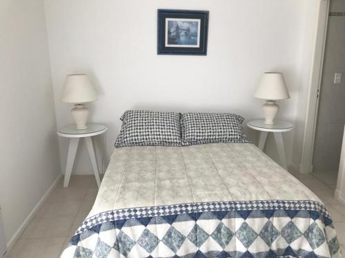 1 dormitorio con 1 cama y 2 mesas con lámparas en Edificio Long Beach, en Punta del Este