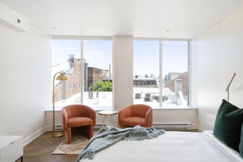 1 dormitorio con 2 sillas, 1 cama y ventana grande en Sonder Saint Paul en Montreal