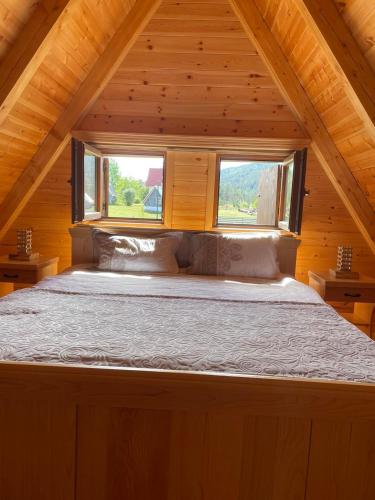 a bed in a wooden cabin with a window at Guest House LENA in Žabljak