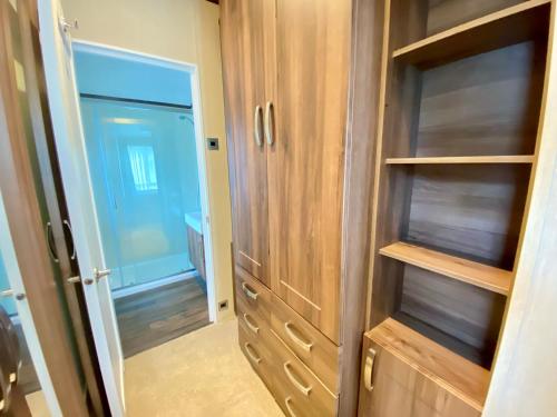 a walk in closet with wooden cabinets and a door at Wildflower, Premium Plus Hot Tub Lodge in South Cerney