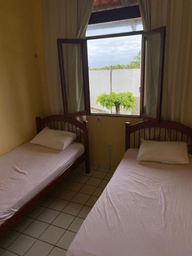two beds in a room with a window at Condomínio Portal do Paraíso in Lucena