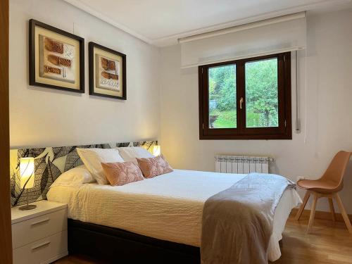 a bedroom with a bed with two lamps and a window at Apartamento Baztán in Elizondo