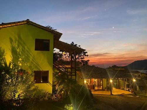 a building with a sunset in the background at Pura Vida Guest House in Ilhabela