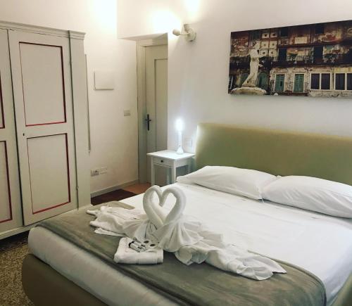 een slaapkamer met een bed met een handdoek in de vorm van een hart bij Palazzo Della Torre Room in Verona