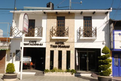 a white building with two balconies on a street at Hotel Tres Marías in San Cristóbal de Las Casas