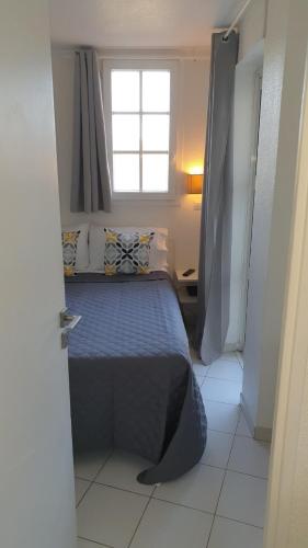 une chambre avec un lit bleu avec une fenêtre dans l'établissement Vacances Cap Esterel Apartment - Agay, à Agay