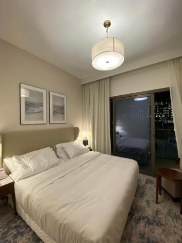 Un dormitorio con una gran cama blanca y una ventana en Apartment the address resort- Two-Bedroom and maid room, en Al Aqah