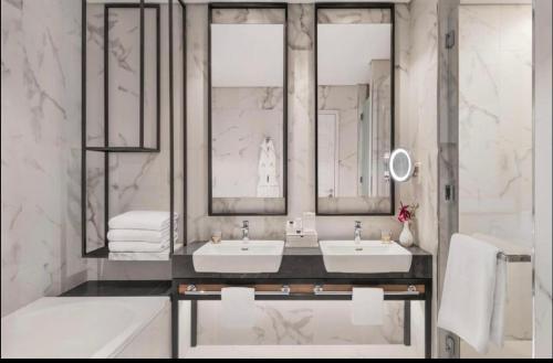 baño con 2 lavabos, bañera y espejos en Apartment the address resort- Two-Bedroom and maid room, en Al Aqah