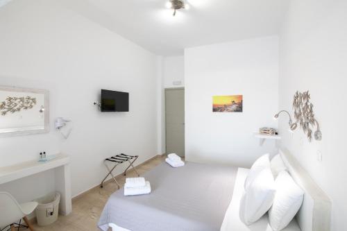 a white bedroom with a bed and a desk at Evas House in Fira