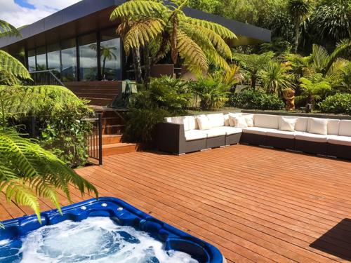 a hot tub sitting on a wooden deck with a couch at Waterfall Bay Glass House in Picton