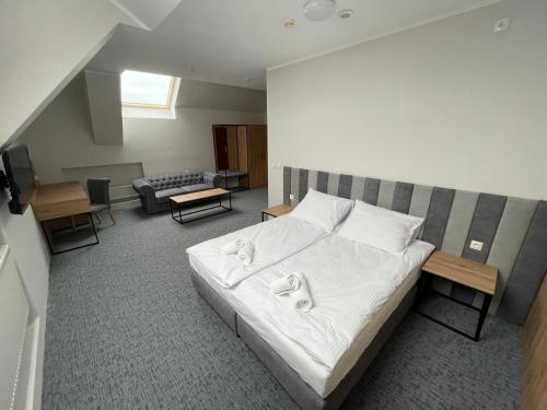 Schlafzimmer mit einem Bett mit weißer Bettwäsche und Kissen in der Unterkunft Hotel Wodnik in Krotoszyn