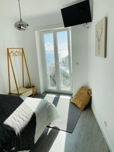 a bedroom with a bed and a large window at DDM Studio - O paraíso do Sítio da Nazaré in Nazaré