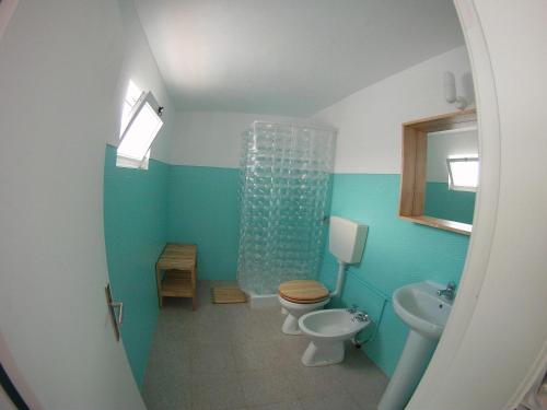 a blue bathroom with a toilet and a sink at Ahoy Porto Covo Hostel in Porto Covo