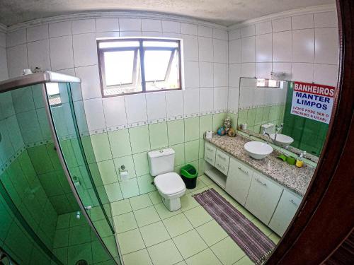 a green and white bathroom with a toilet and a sink at Hostel e Pousada Bahia Beach in Itanhaém