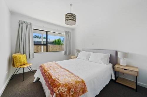 1 dormitorio con cama, ventana y silla en Greytown Getaway - Greytown Holiday Home en Greytown