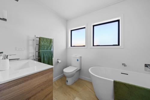 a white bathroom with a tub and a toilet at Greytown Getaway - Greytown Holiday Home in Greytown