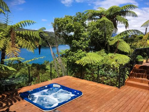 a hot tub on a wooden deck with a view of the water at Waterfall Bay Glass House in Picton