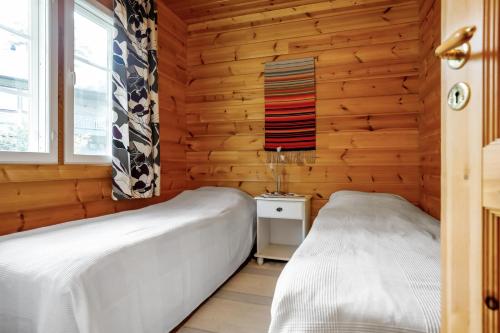 Duas camas num quarto com paredes de madeira em Cottage Kivitatti em Sysmä
