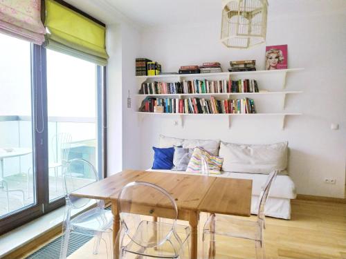 a table and chairs in a room with a book shelf at Warsaw Concierge Vistula Apartment in Warsaw