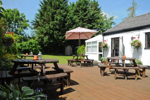 a patio with picnic tables and an umbrella at The New Court Inn in Usk