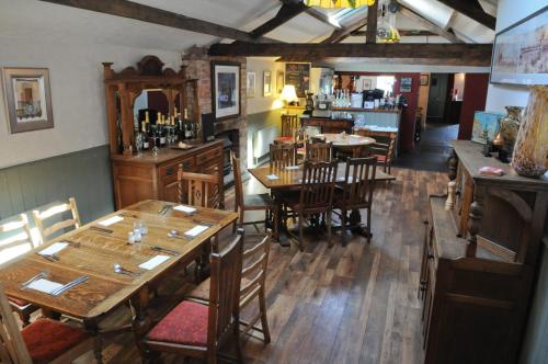 un ristorante con tavoli e sedie in legno e un bar di The New Court Inn a Usk